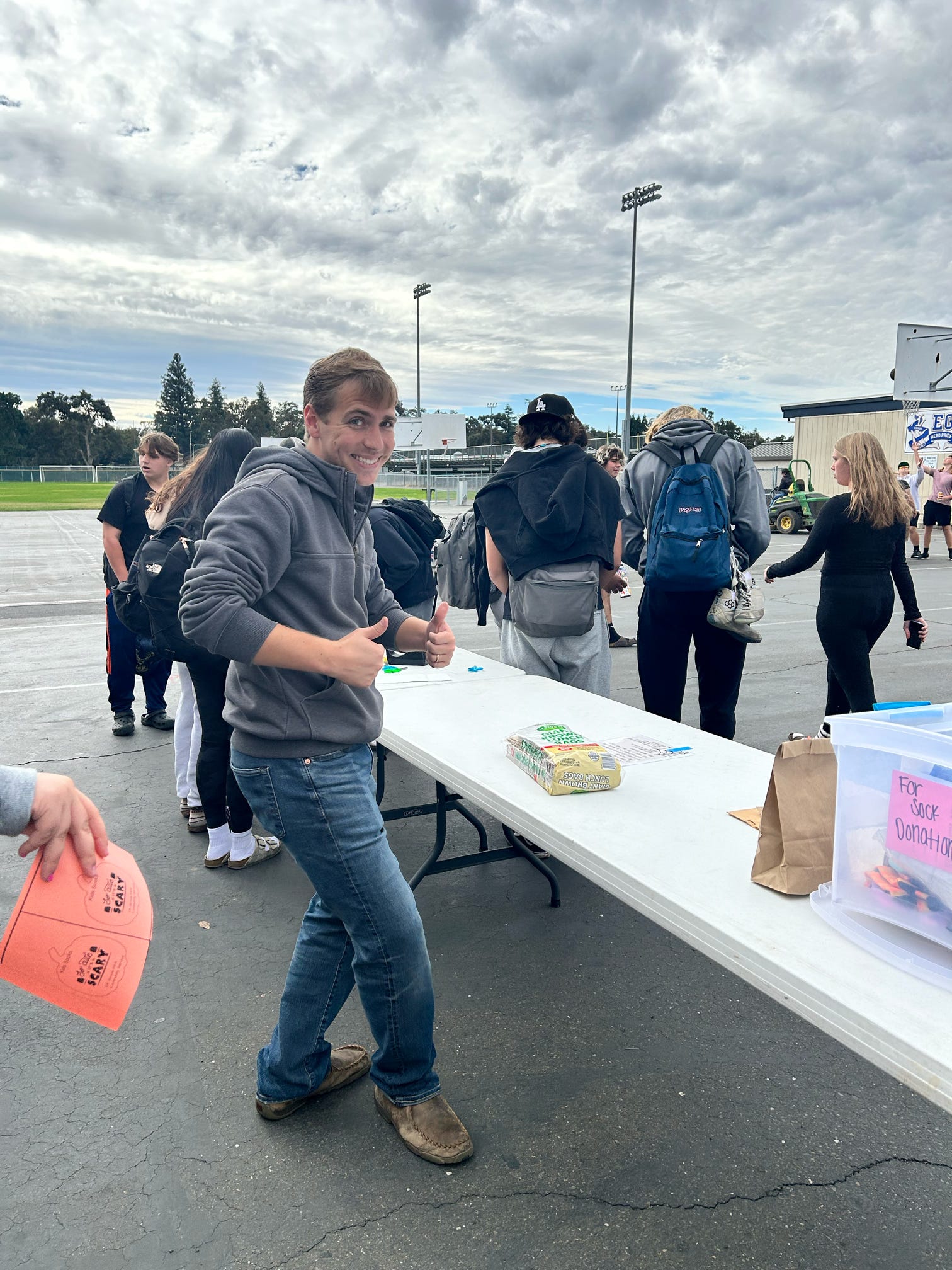 Student volunteer giving thumbs up at event