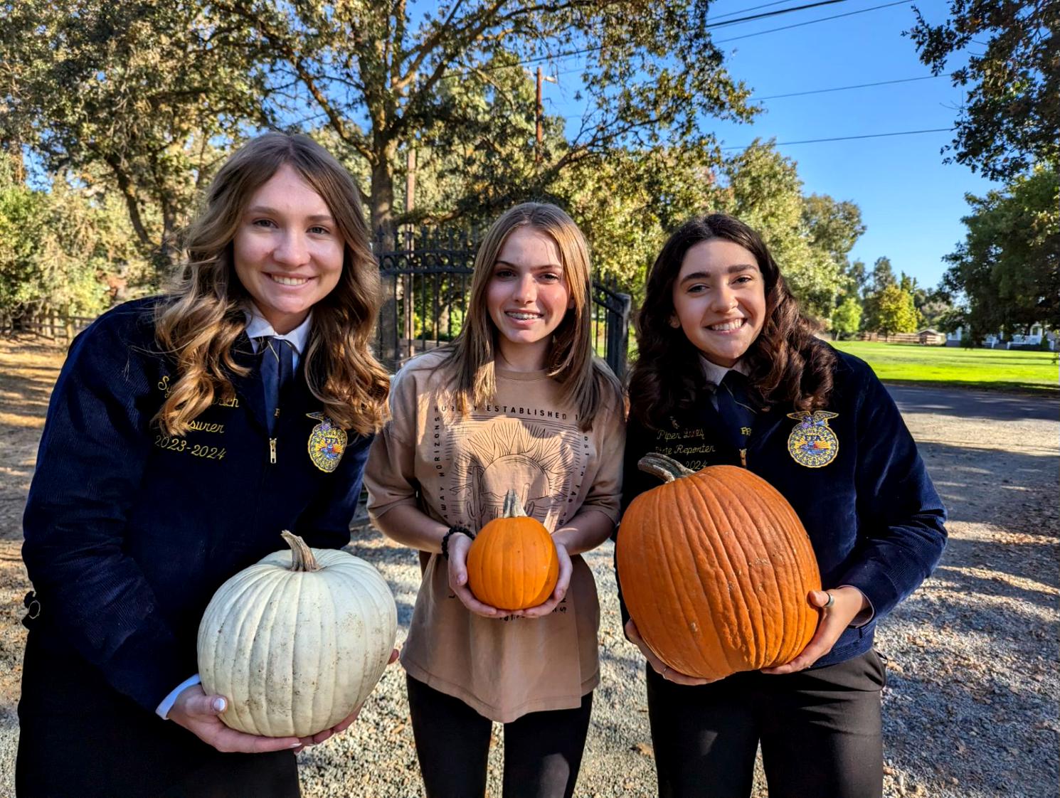 State officers holding pumpkins and smiling